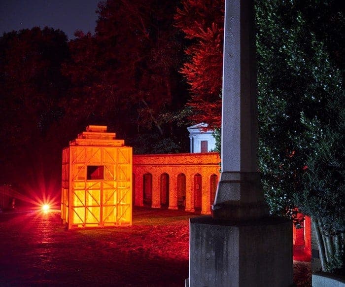 The lit installation seen beyond a stone wall