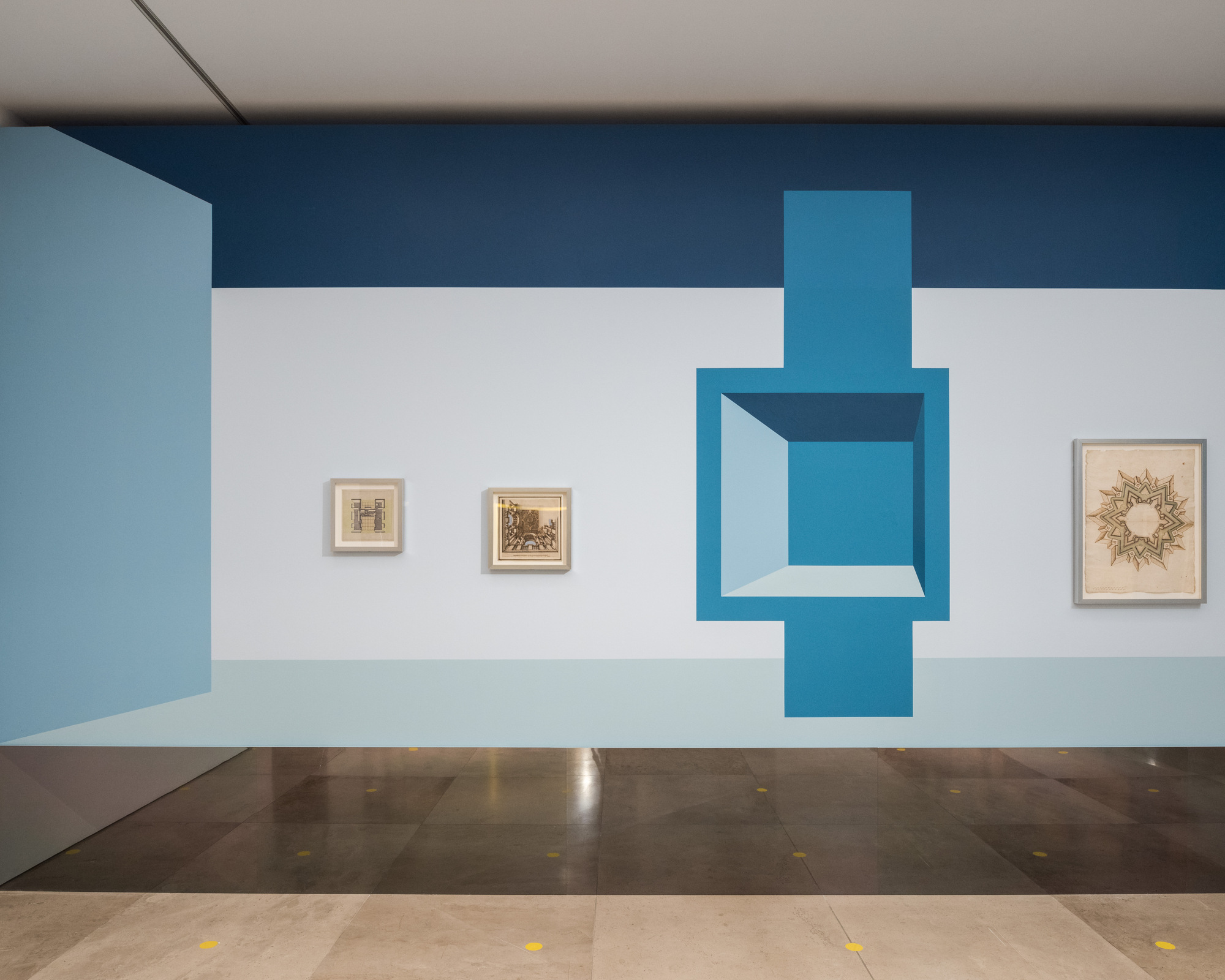 Disappear Here: A painted blue opening beside framed architectural drawings