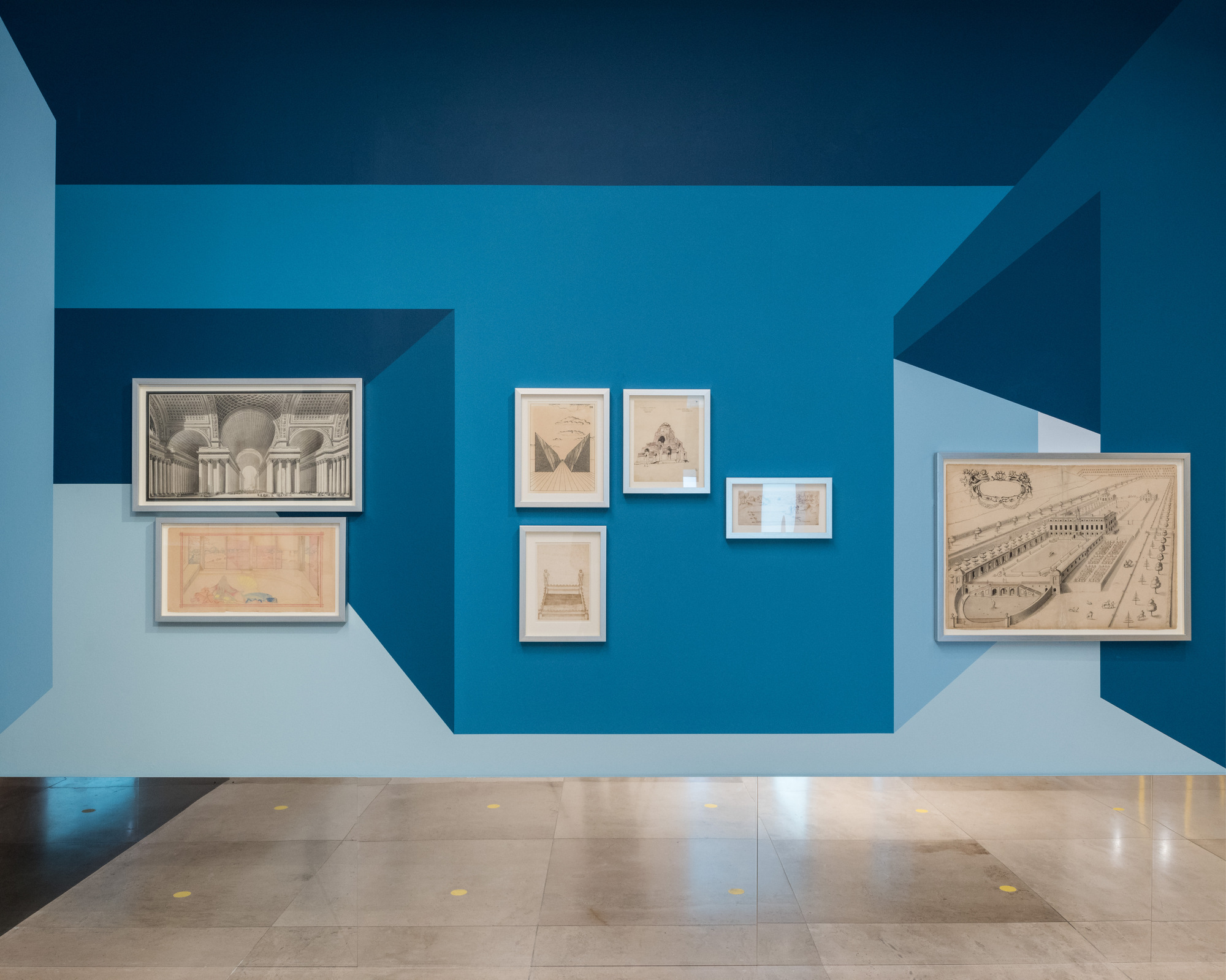Disappear Here: Seven framed architectural drawings arranged on a blue wall