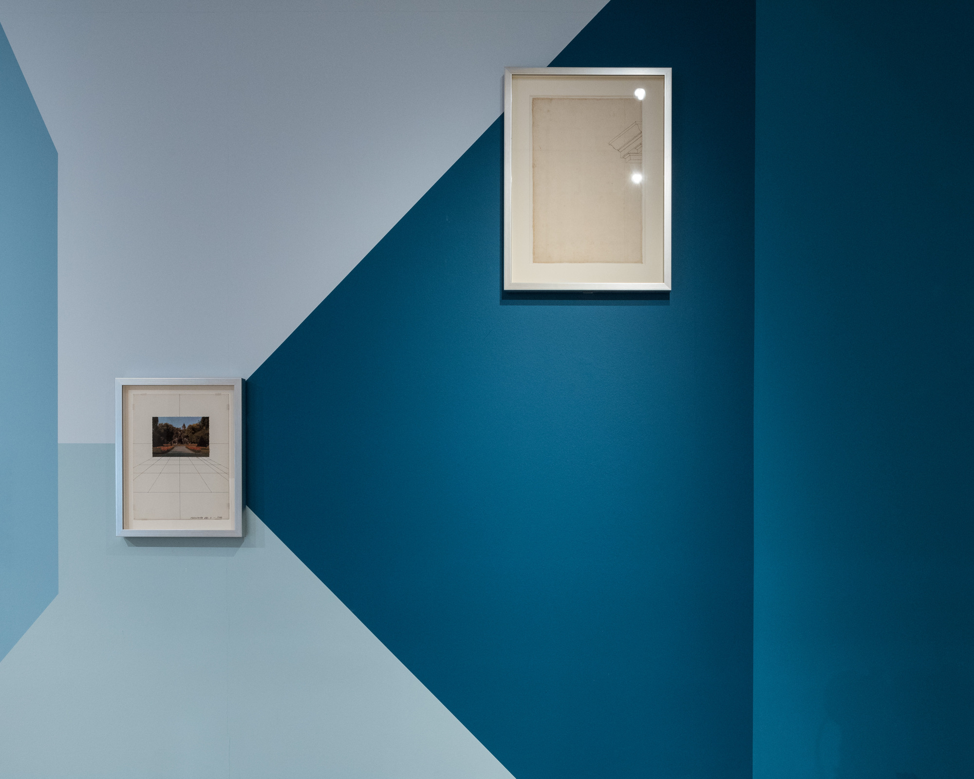 Disappear Here: Two framed works separated by a diagonal boundary between pale and dark blue