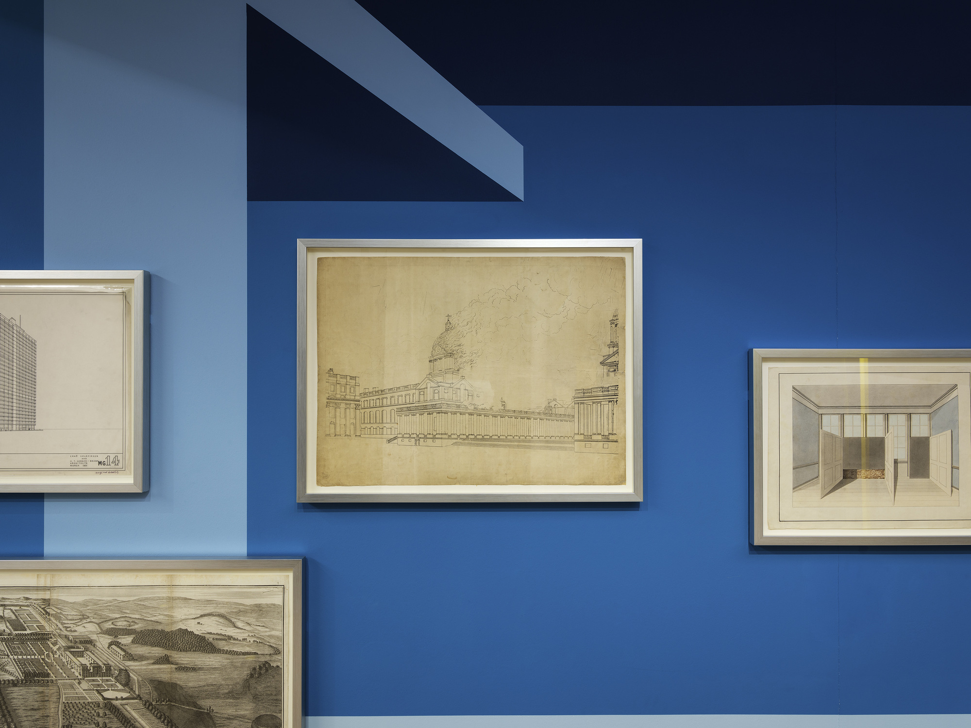 Disappear Here: Detail of framed architectural drawings against the blue wall