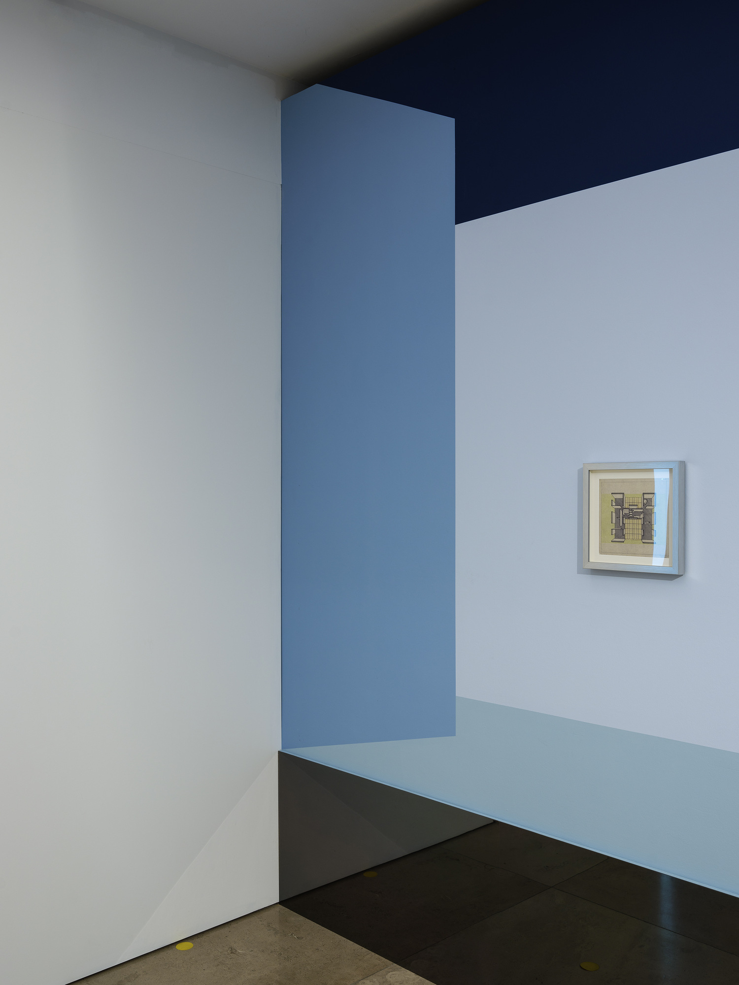 Disappear Here: A small framed drawing at the junction of pale blue wall surfaces and a mirrored base