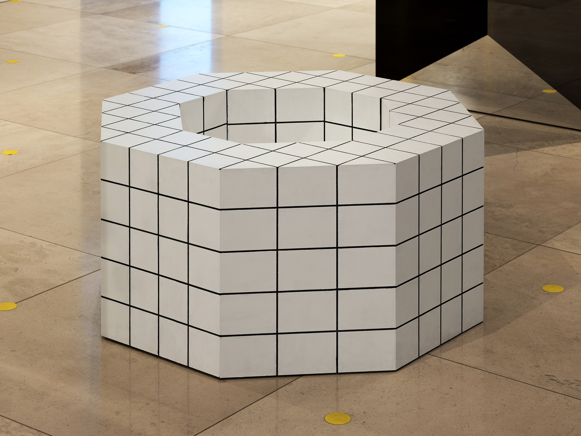 Disappear Here: White faceted ring-shaped seat marked with a black grid