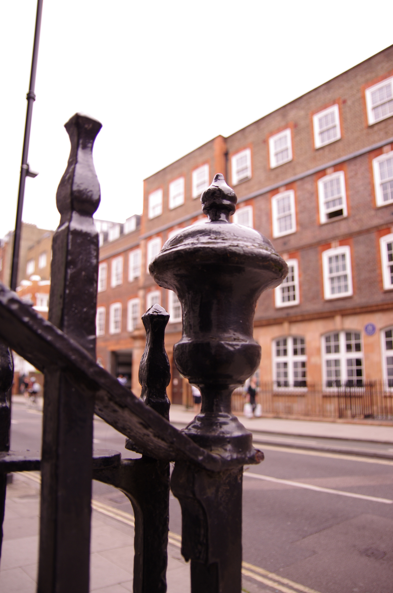 The urn-shaped finial on black street railings, with buildings behind